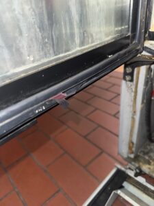 Damaged door seal on a commercial fridge showing cracks and gaps, leading to cold air loss and reduced efficiency.